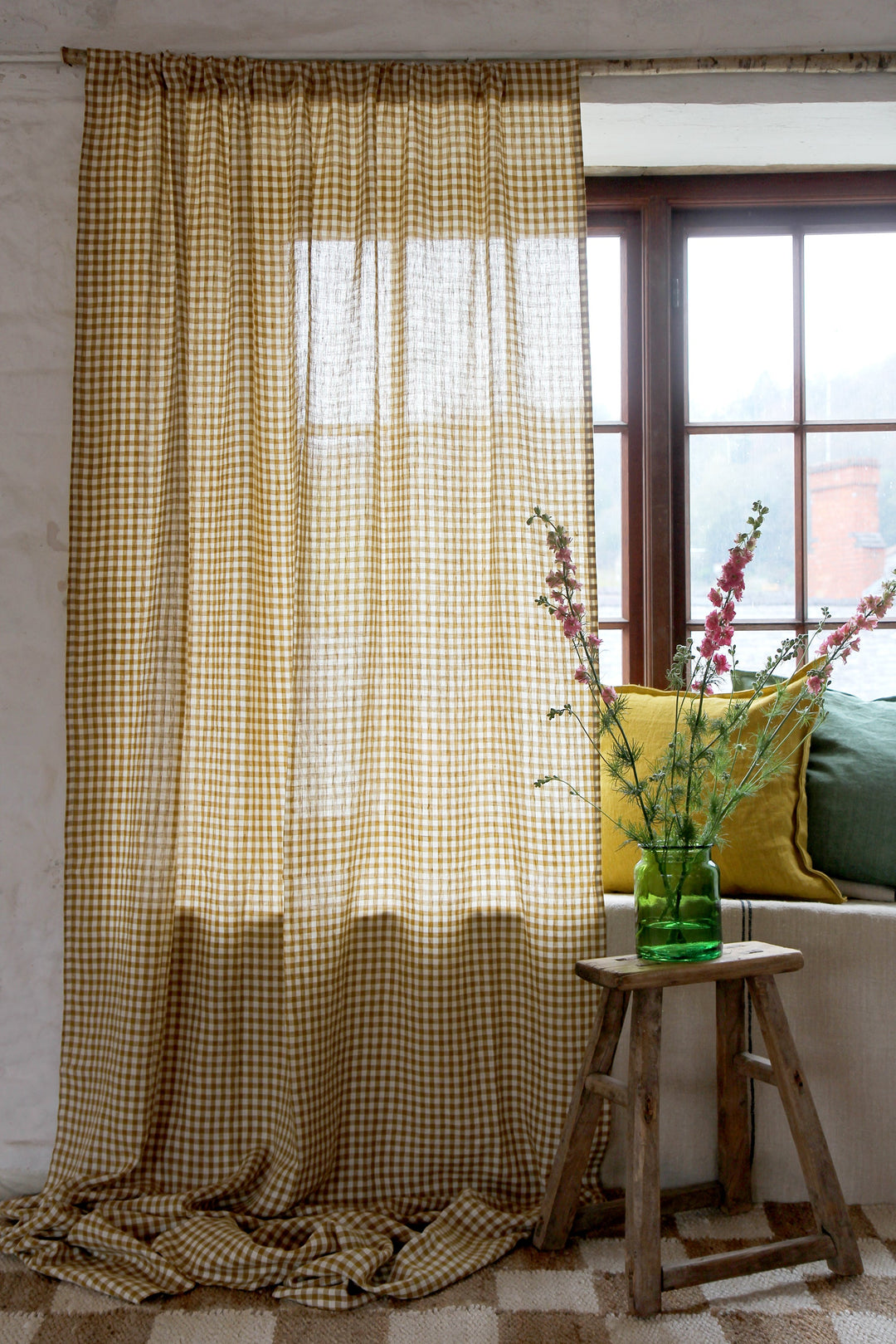 mustard gingham curtain hanging in window with vintage stool and vase of flowers