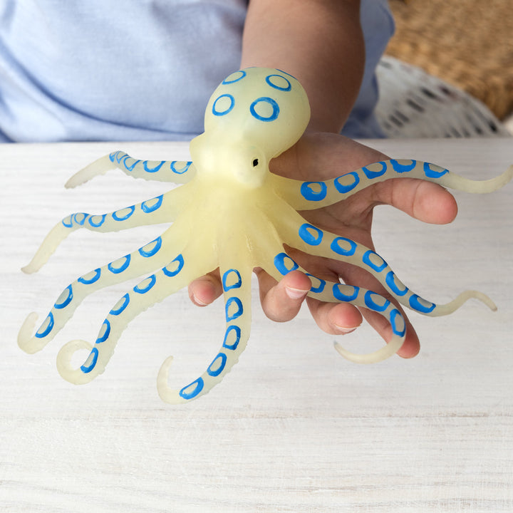 Toy octopus with blue rings held by a child's hand on a light surface