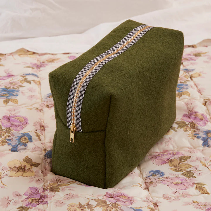 Green wedge-shaped pillow with a zipper on a floral bedspread