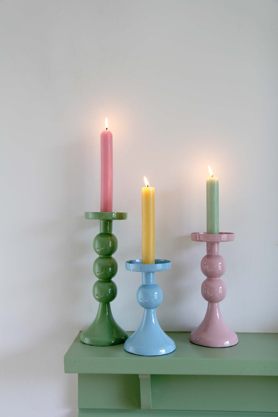 group of metal candle holders with bobble stems with colourful dinner candles on mantlepiece