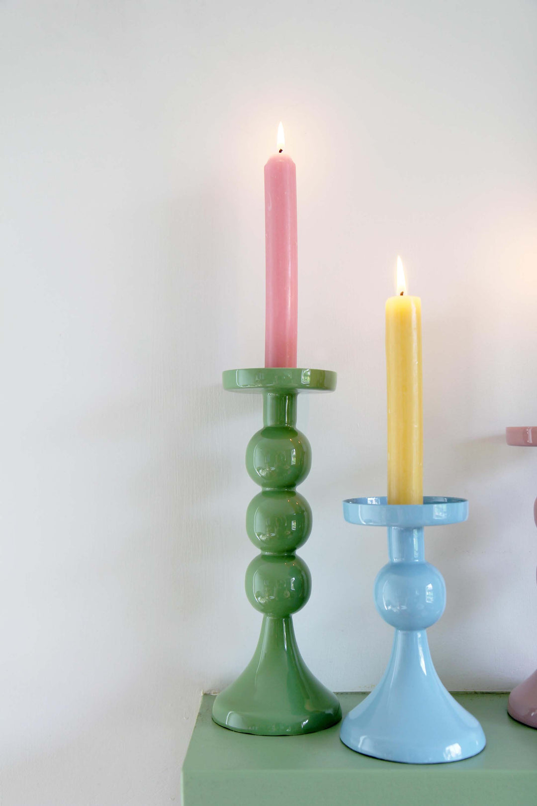green metal candle holders with bobble stem with colourful dinner candle on mantlepiece