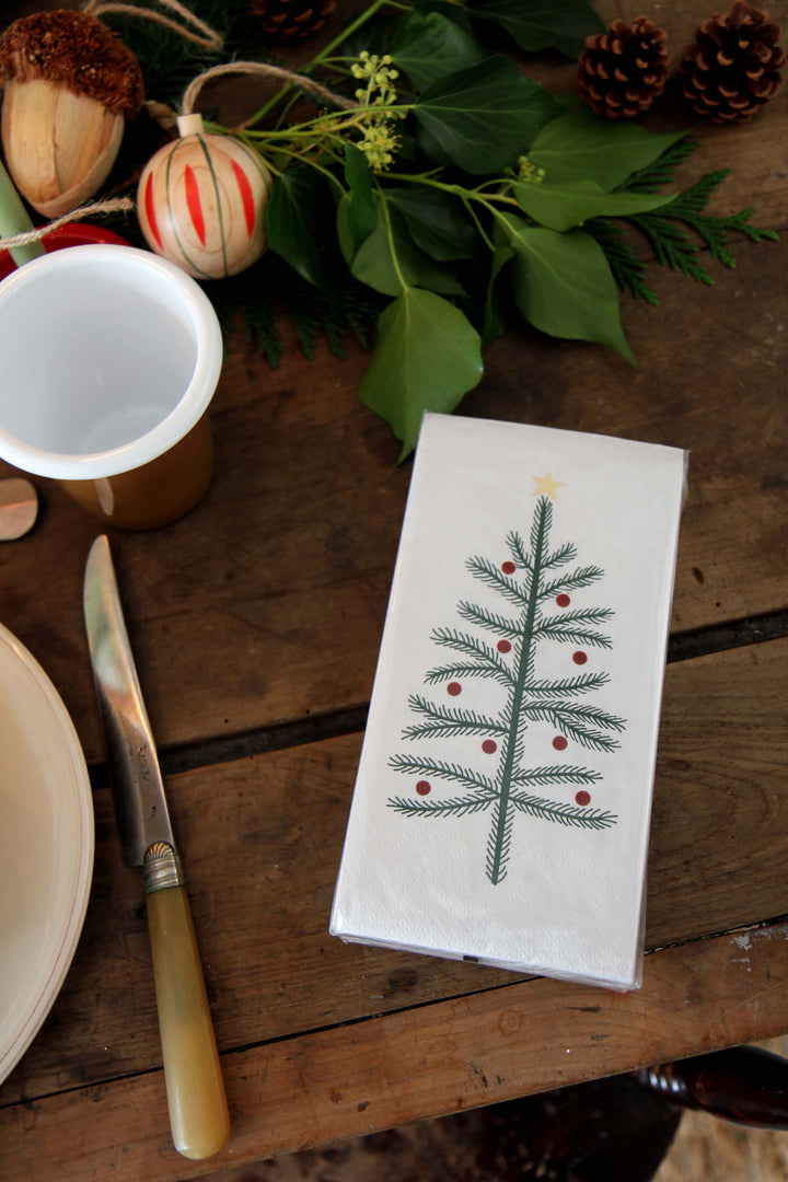 Napkin with Christmas tree design on a wooden table with festive decorations.