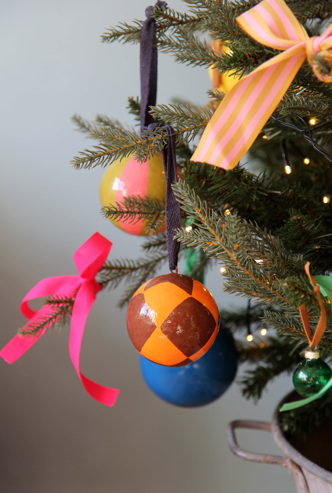 Colorful Christmas ornaments on a decorated tree with pink ribbons.