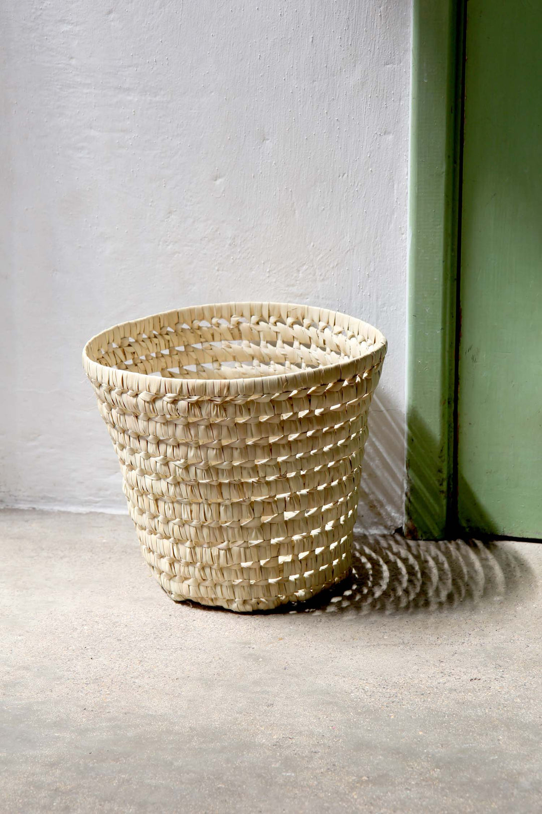 Woven basket on a plain floor with a neutral background
