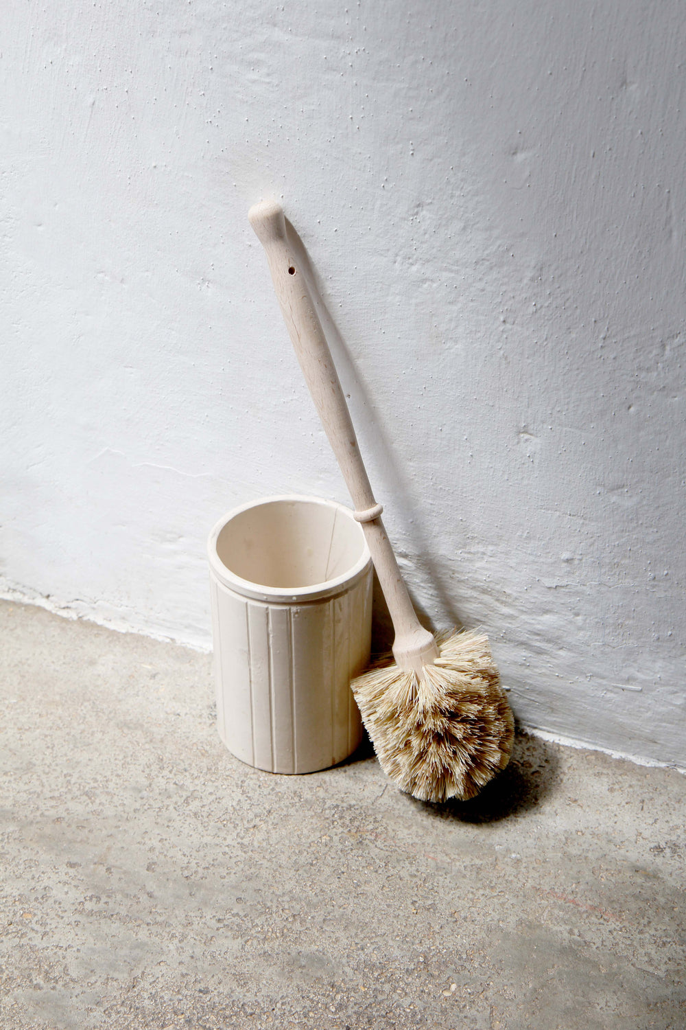 Cleaning brush and container against a white wall