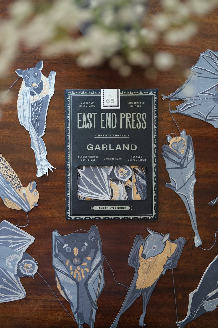 Pack of 'Garland' stickers by East End Press on a wooden surface with decorative elements.