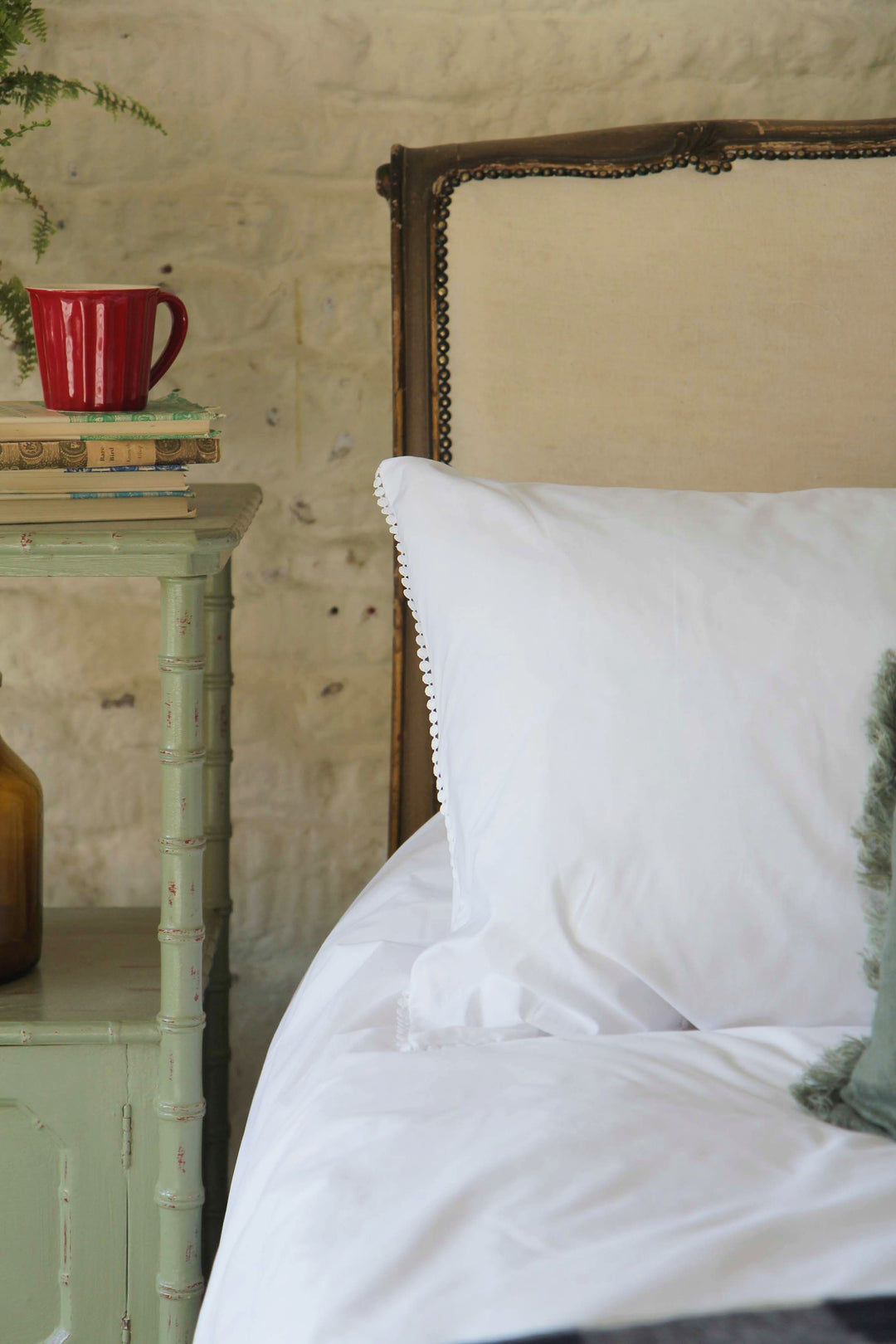 antique french bed with white bobble trimmed pillowcase