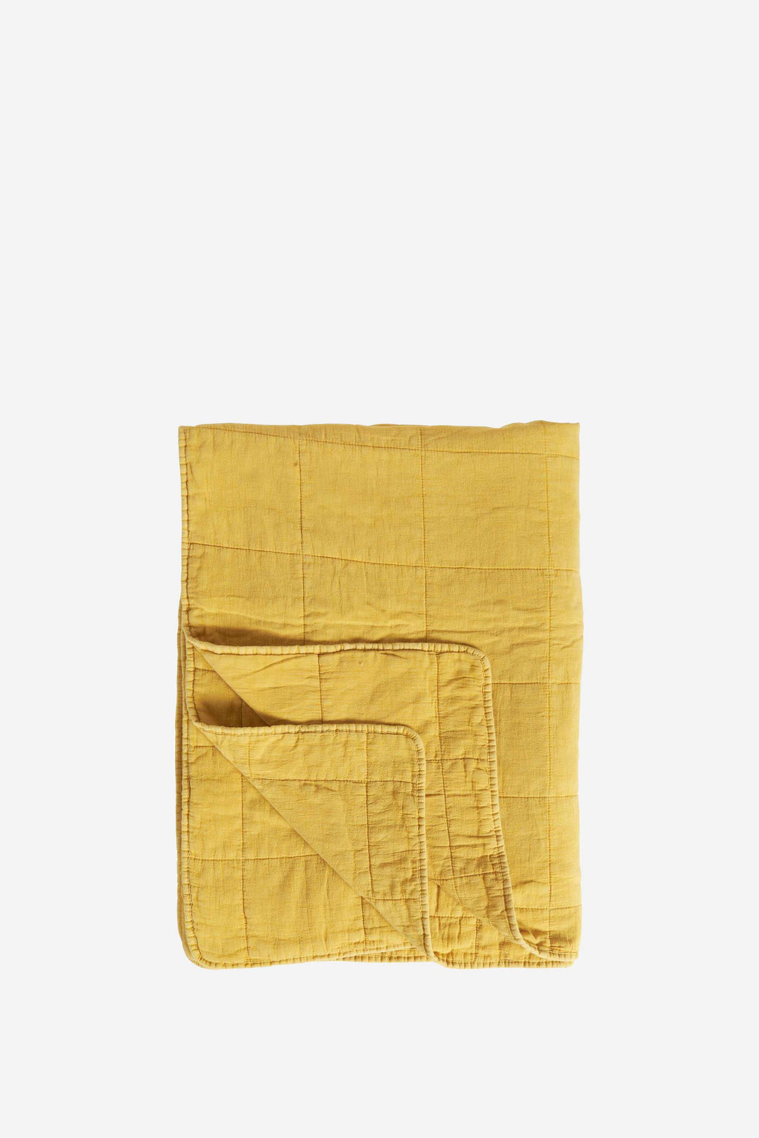Folded mustard yellow quilt on a white background