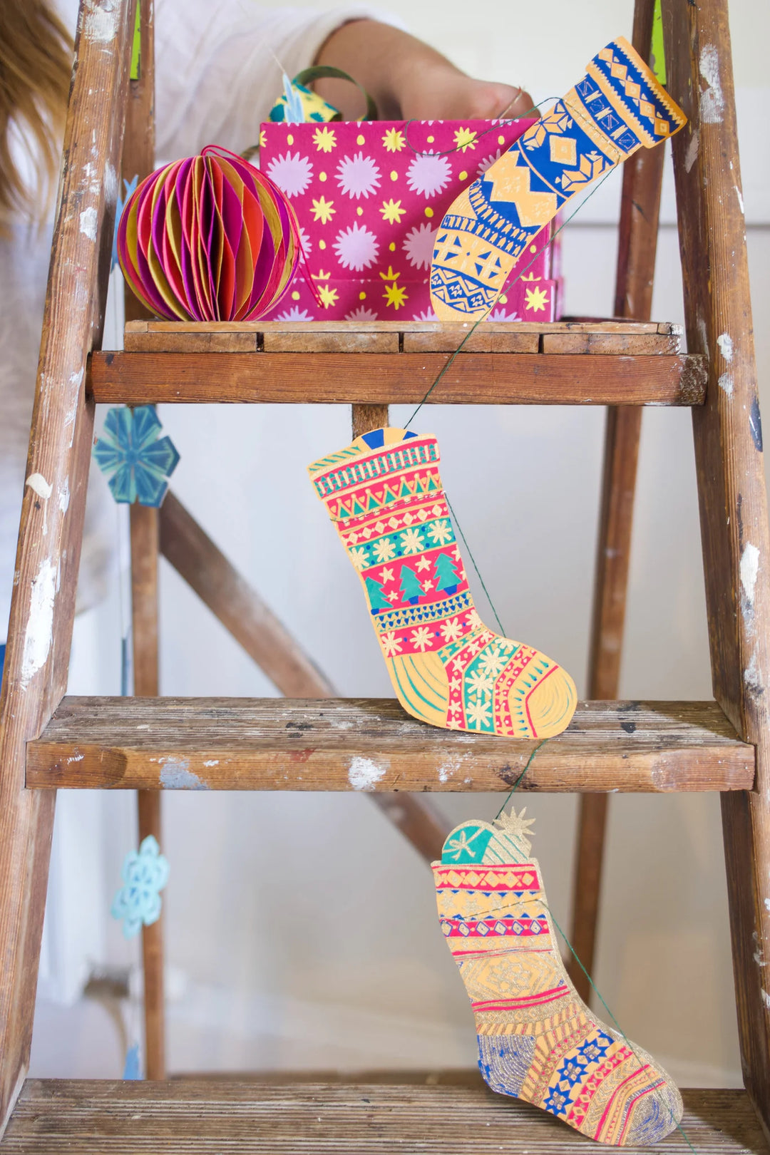 Colorful patterned xmas stockings on a wooden ladder with a white background