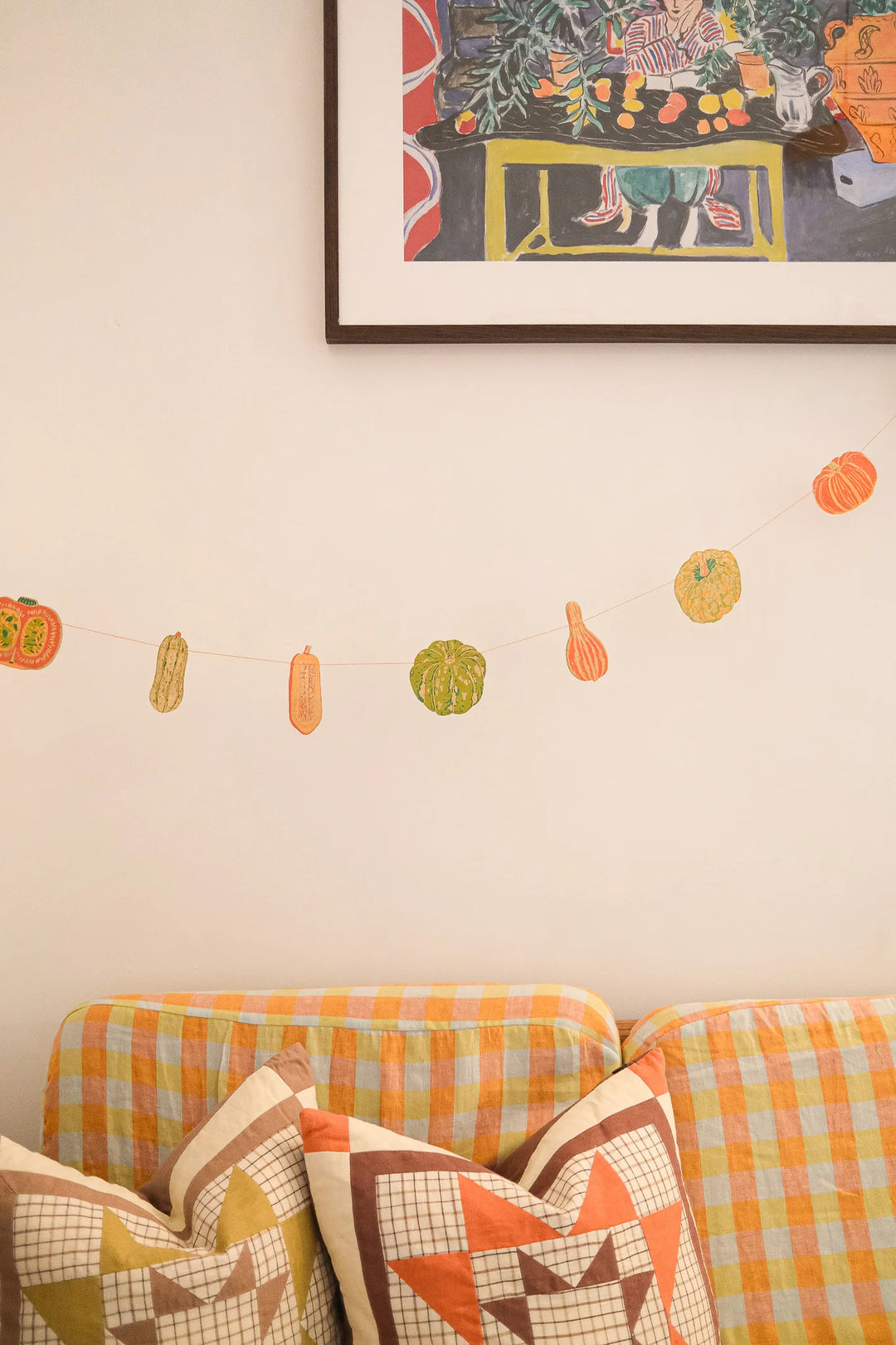 Decorative wall with a plaid couch, colorful pillows, and autumn-themed decorations.