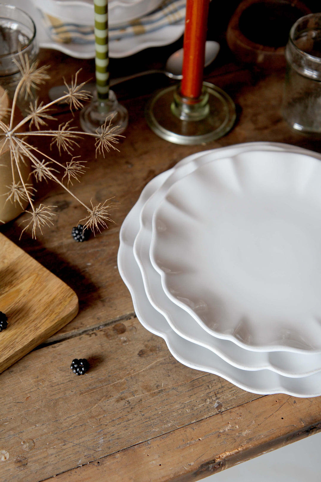 Stack of white ceramic plates on a wooden surface with decorative elements.