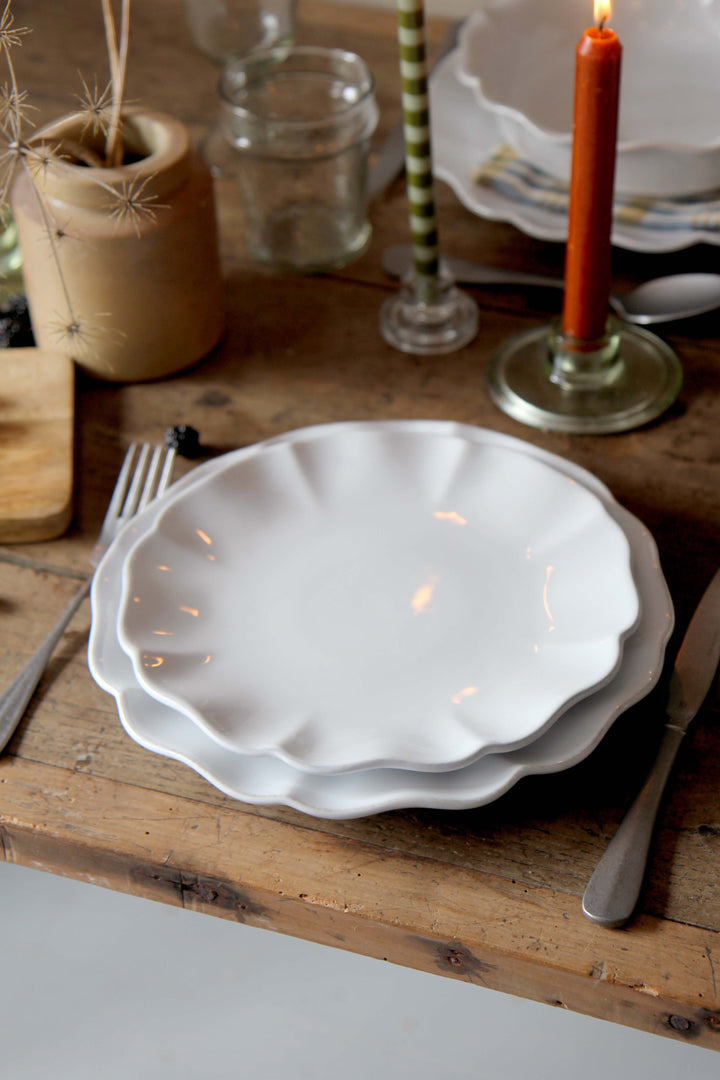 White ceramic plates on a wooden table with candles and cutlery