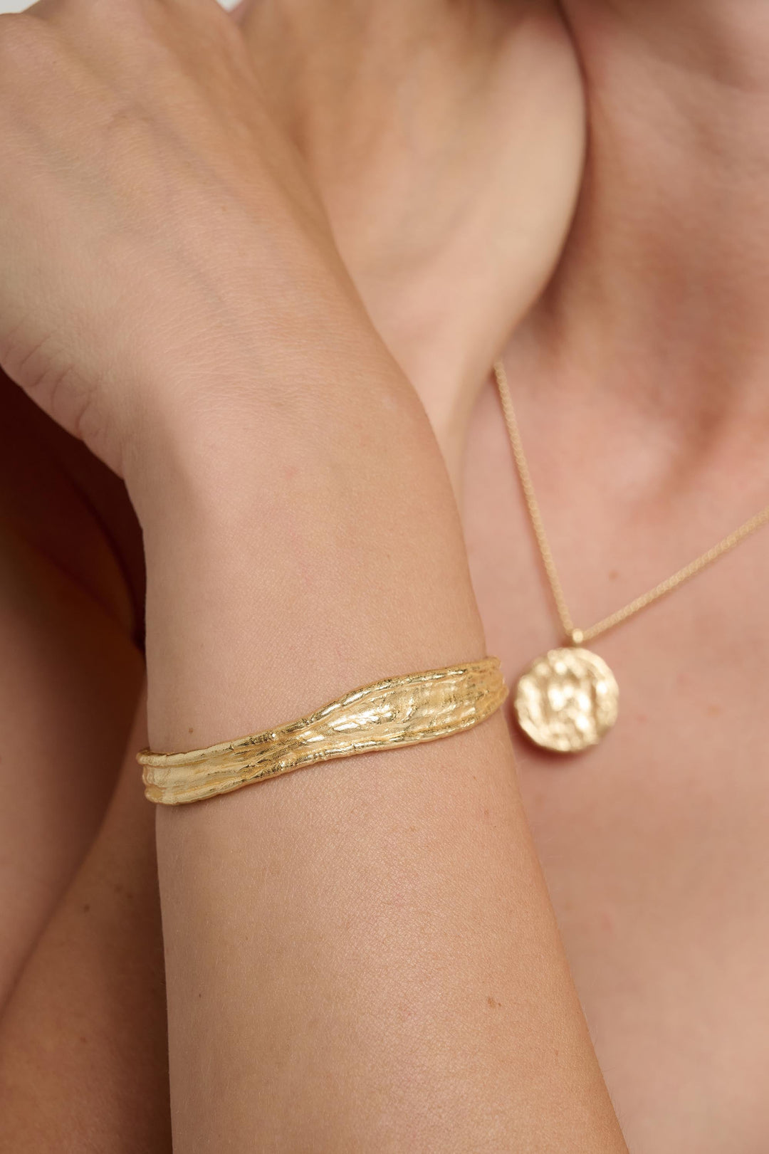 Gold bracelet and necklace on a person's wrist and neck