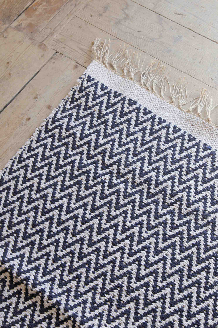 navy and cream jute and cotton woven zigzag rug on wooden floor boards