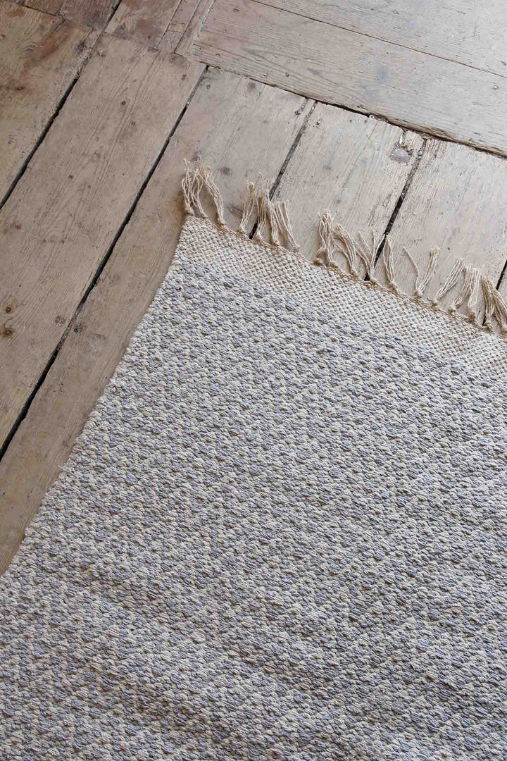 silver and cream jute and cotton woven zigzag rug on wooden floor boards