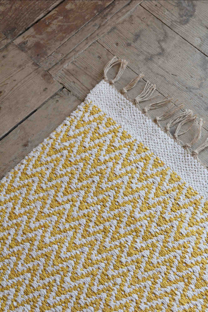 yellow and cream jute and cotton woven zigzag rug on wooden floor boards