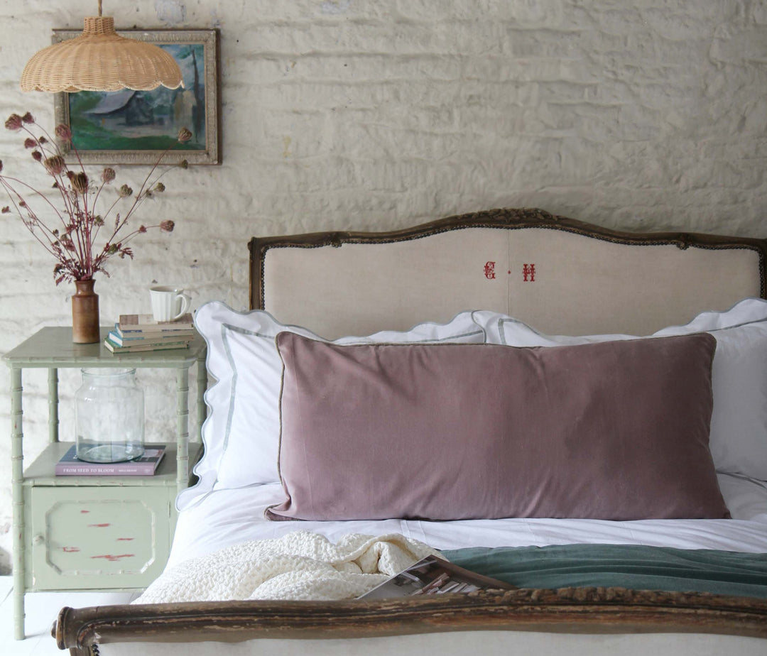 pink velvet bolster cushion on antique french upholstered bed