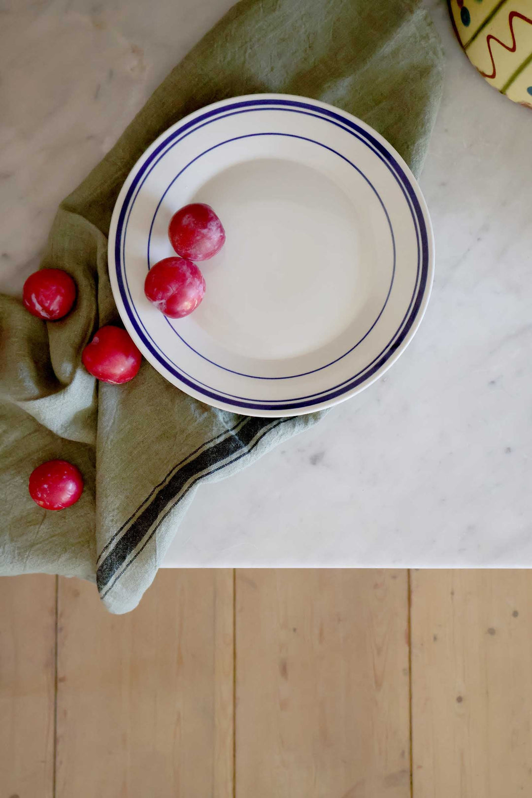 dinner plate with plums and linen t-towel