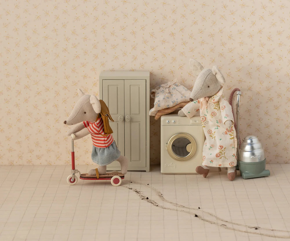 Miniature scene with toy mice and household items against a floral wallpapered wall.