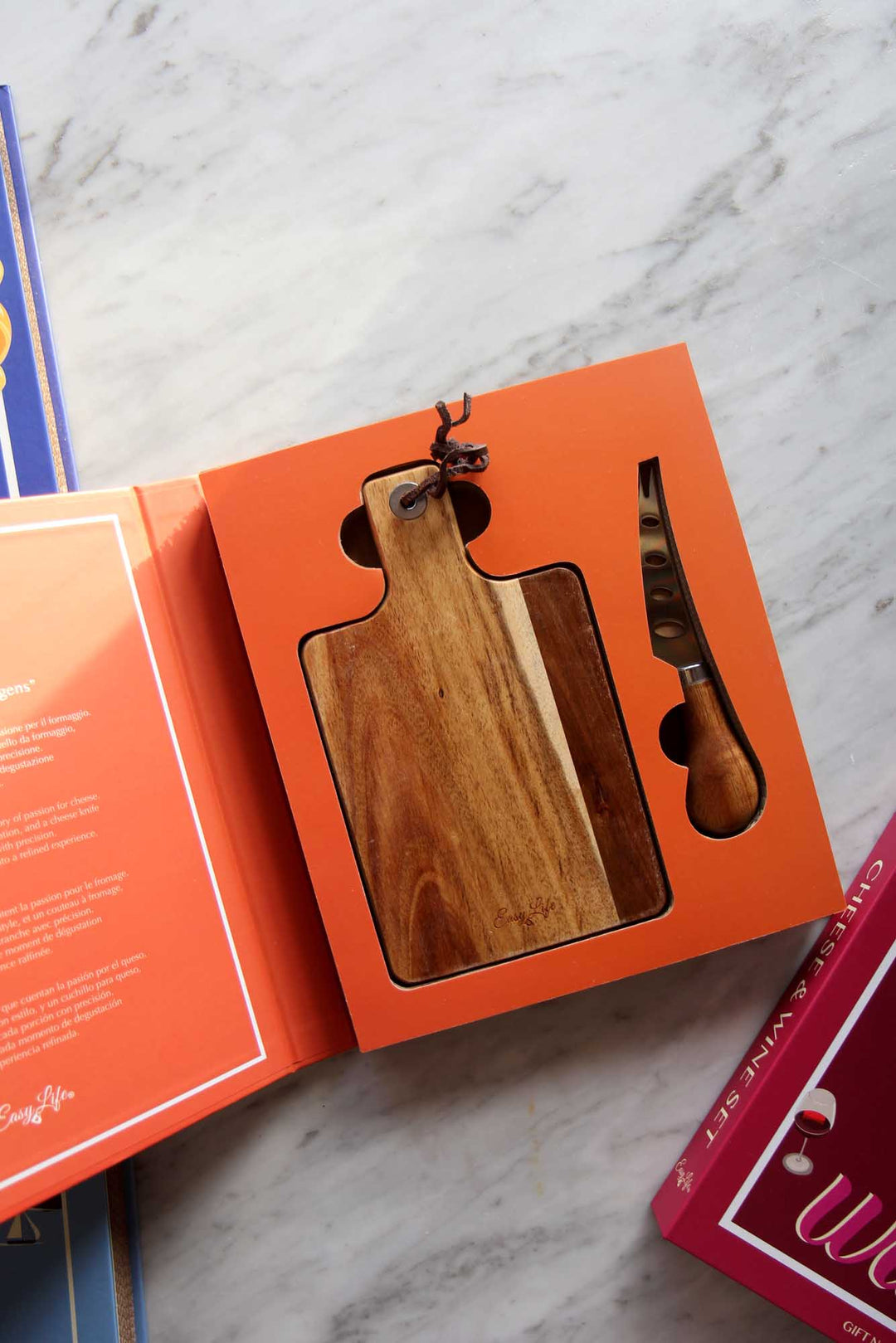 Wooden cutting board and knife set in an open book on a marble surface