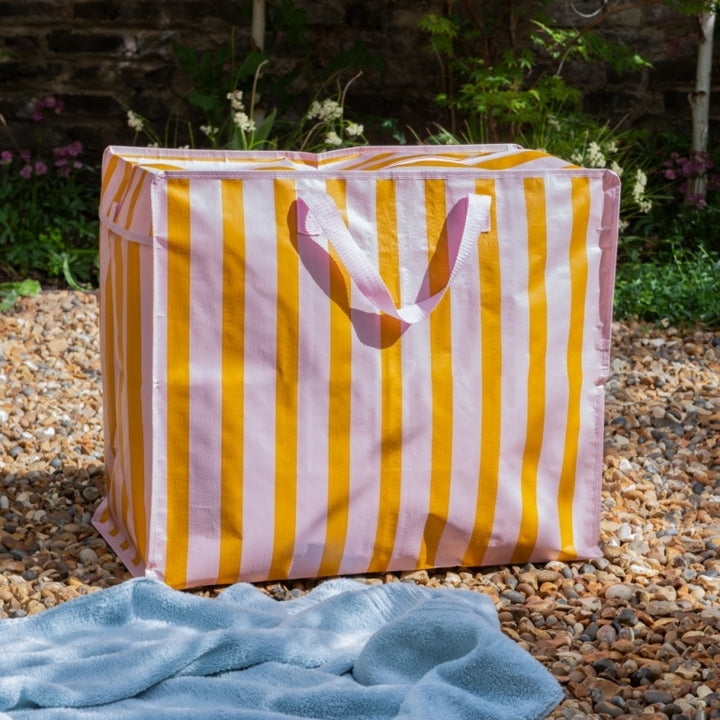 Yellow and pink striped storage cube with a heart design on a stone surface outdoors.