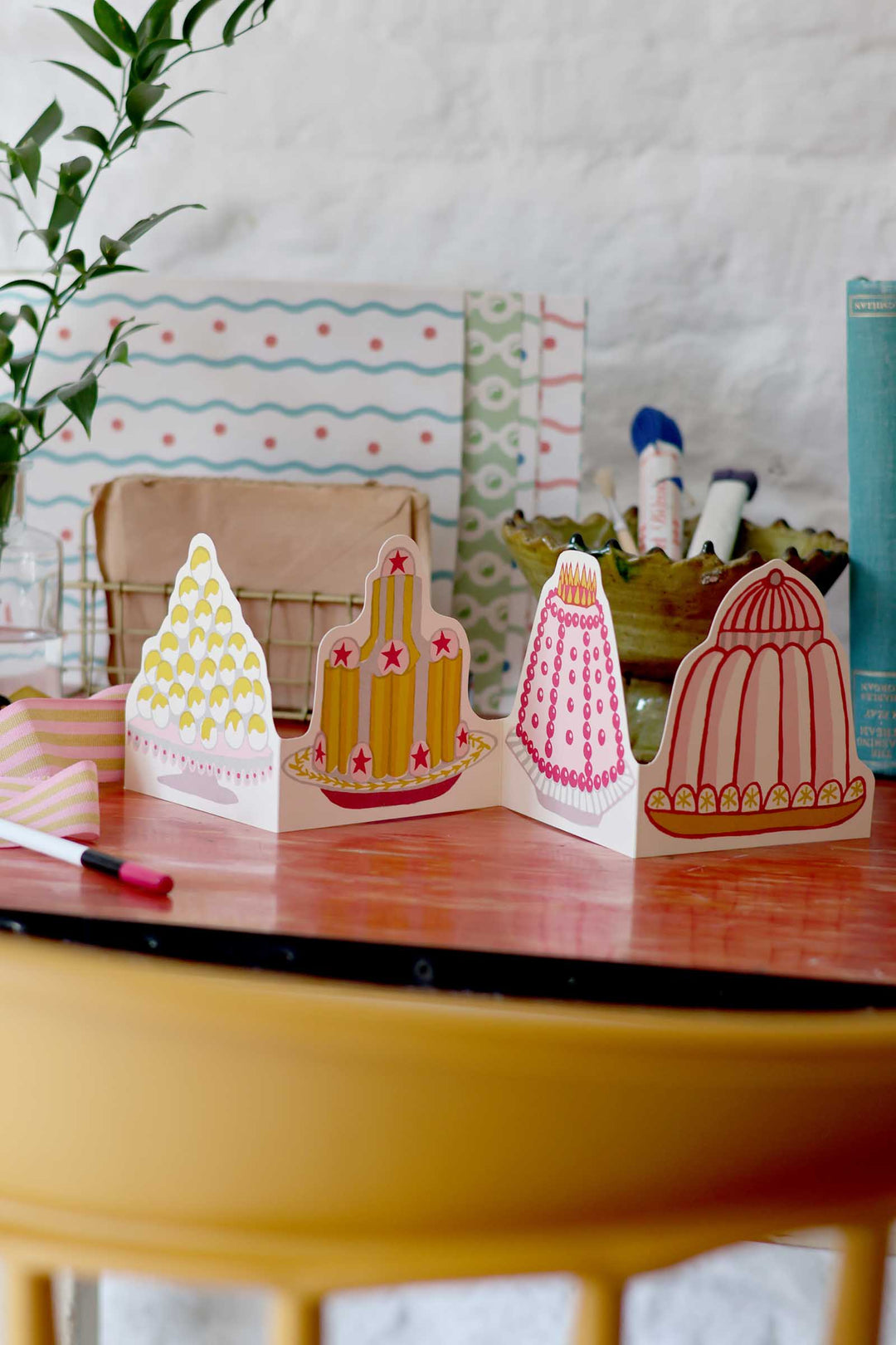 Decorative paper cutouts of cacti on a table with a plant and colorful background