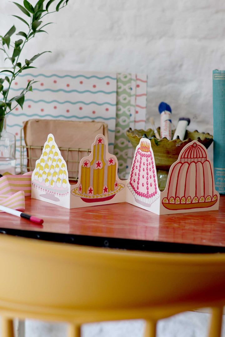 Decorative paper cutouts of cacti on a table with a plant and colorful background