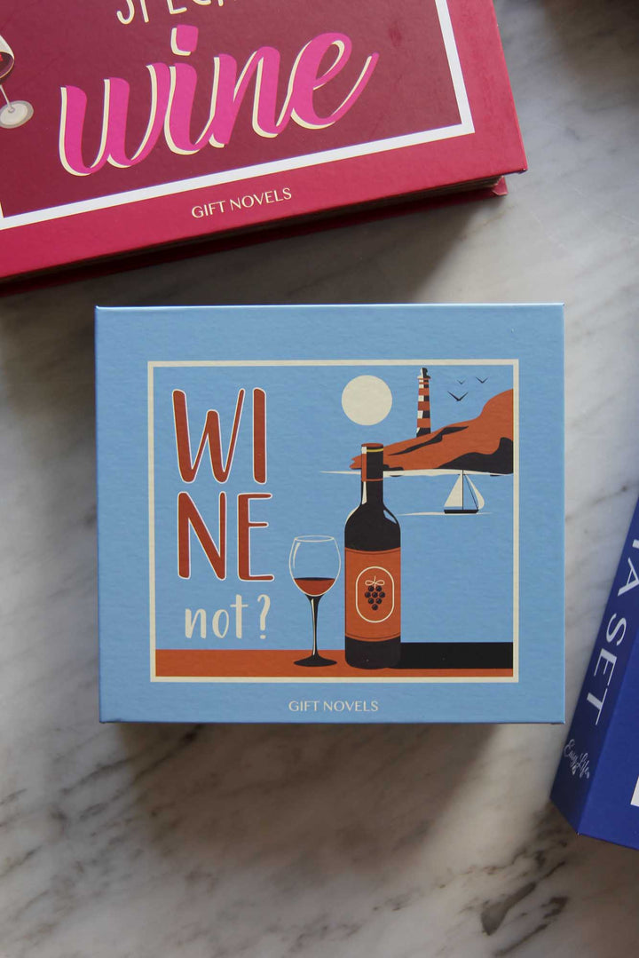 Blue box with wine-themed design and text 'WINE not?' on a marble surface.