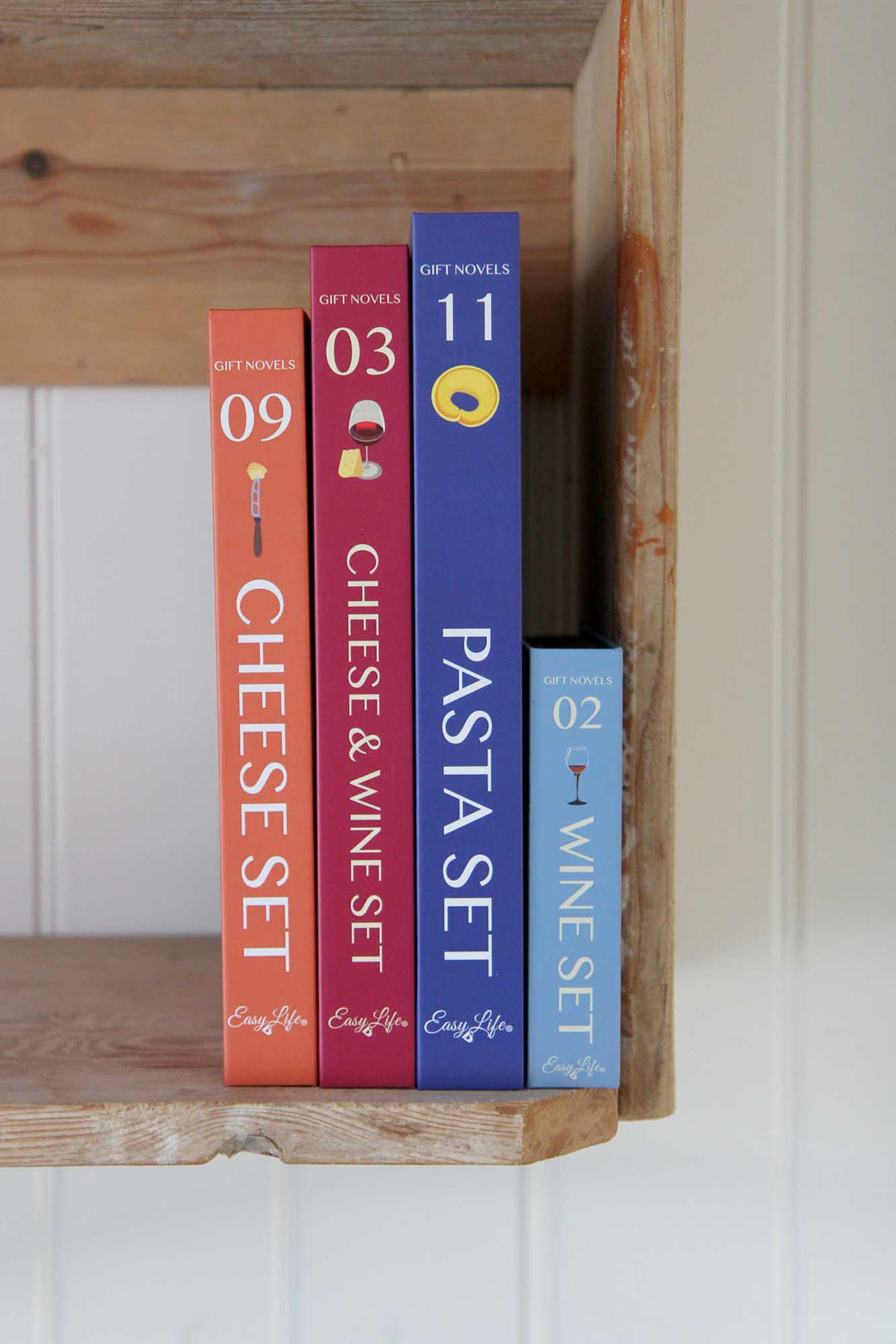 Four books on a wooden shelf with titles related to food sets.