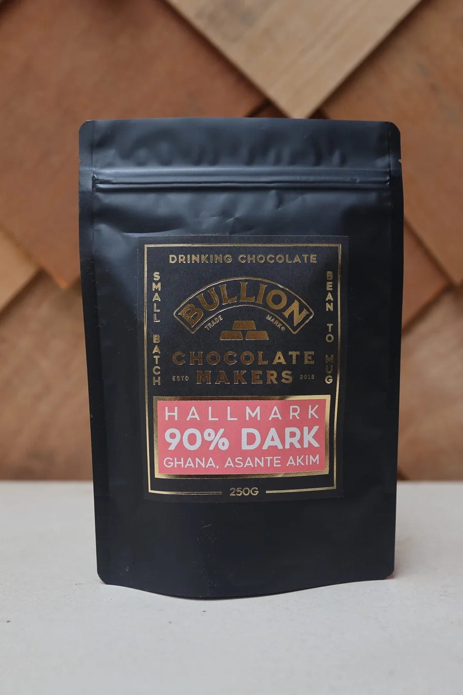 Black packaging of Bullion Chocolate Makers Hallmark 90% Dark Drinking Chocolate on a wooden surface.