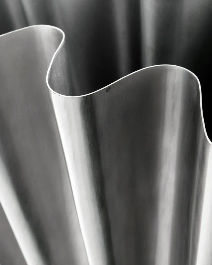 Close-up of a metallic vase with wavy design against a dark background