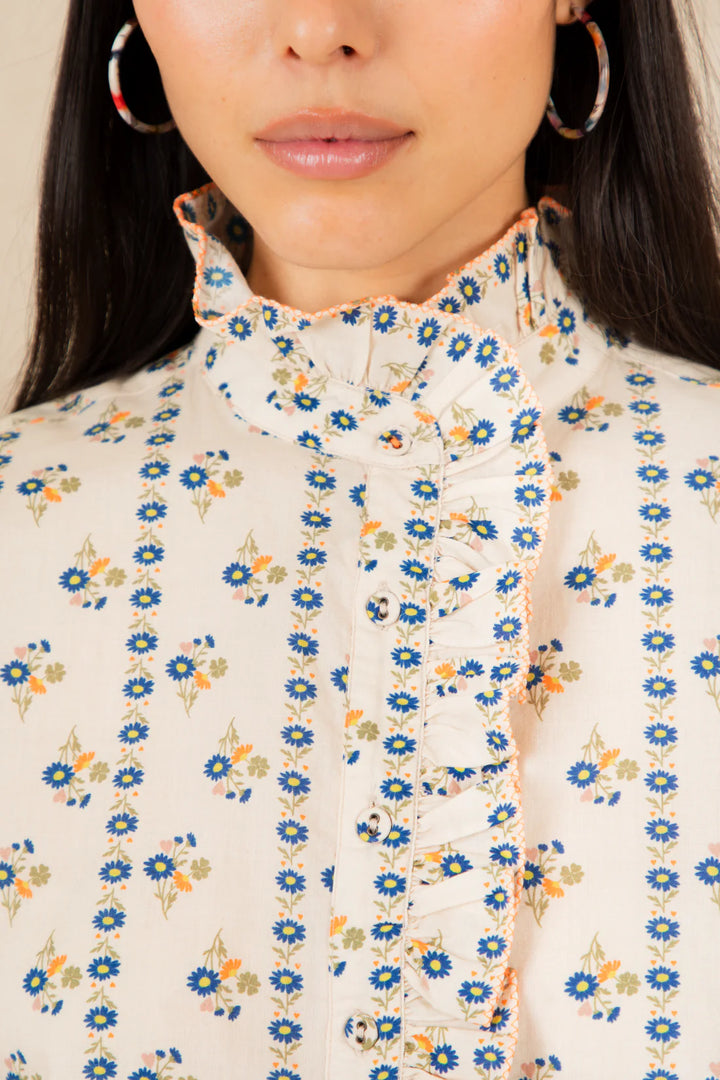 Close-up of a person wearing a floral blouse with a neutral background