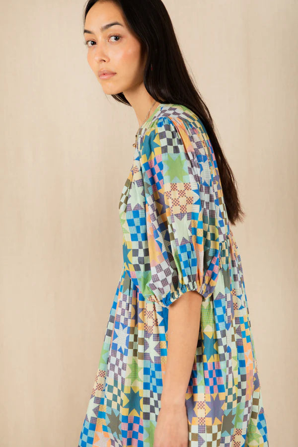 Woman wearing a colorful patterned dress against a beige background