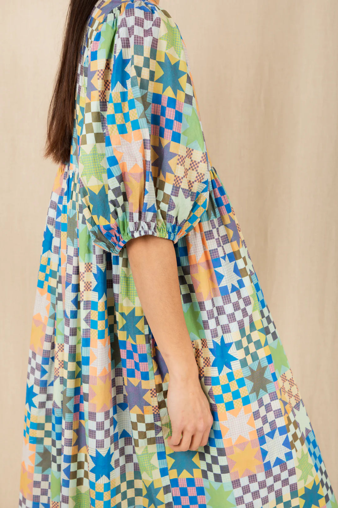 Multicolored patterned dress worn by a person against a beige background