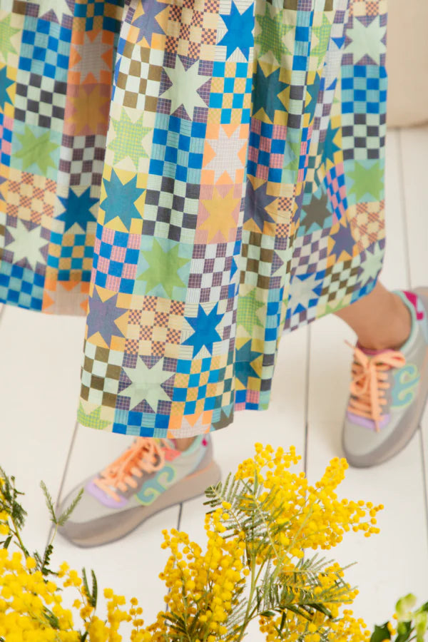 Colorful patterned pants with a child's feet wearing sneakers on a light background