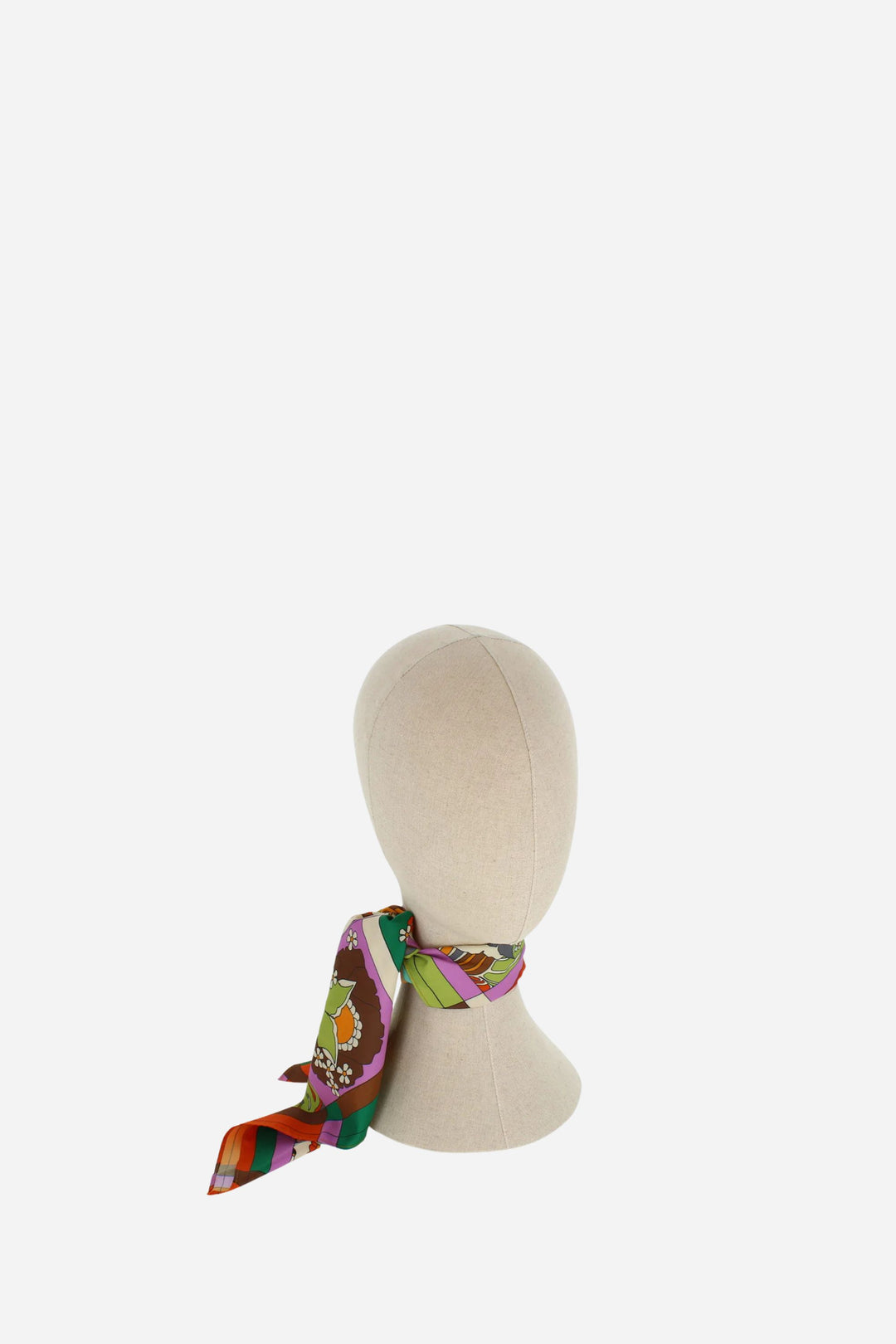Colorful scarf tied around a mannequin head on a white background