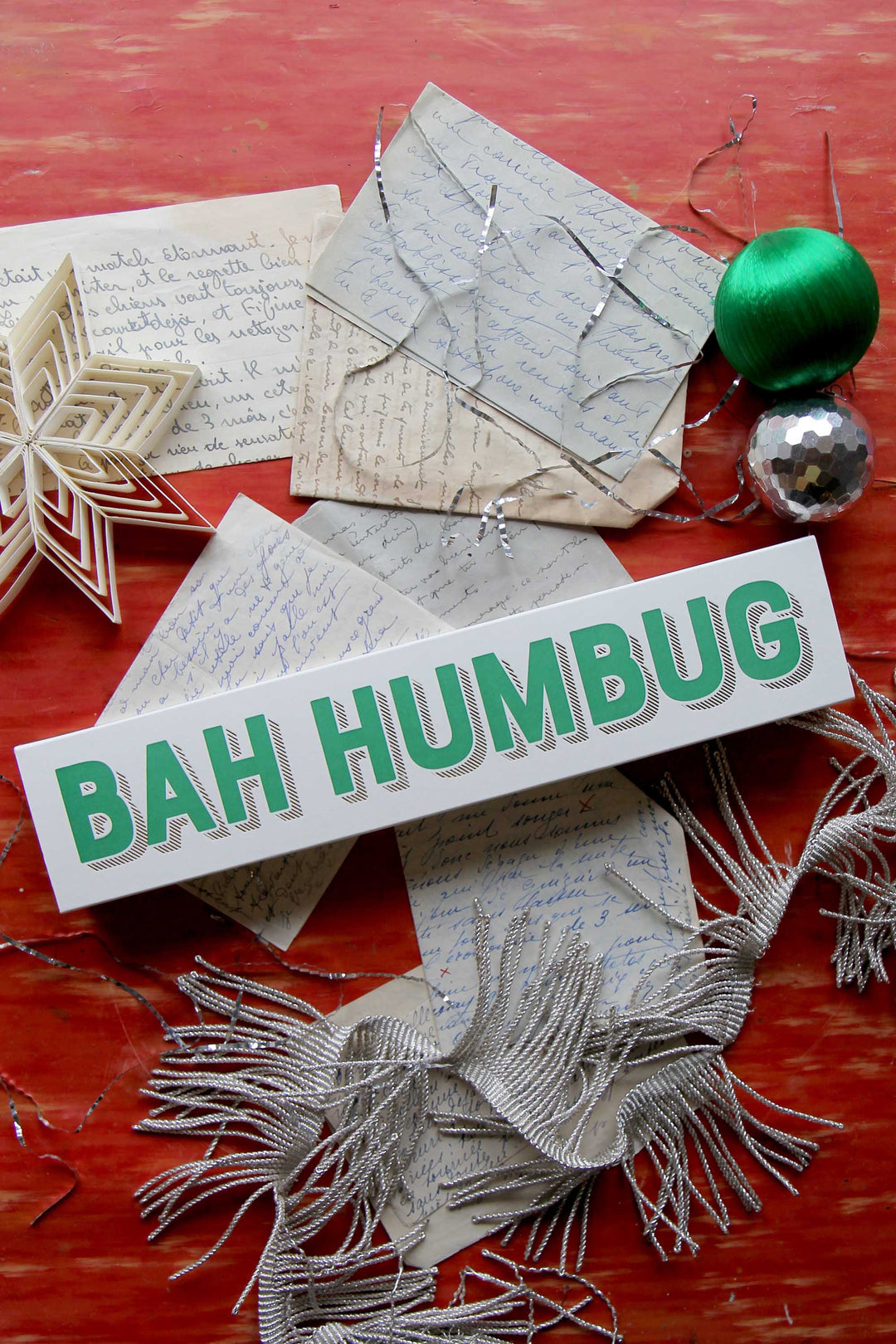 Decorative matches with 'BAH HUMBUG' on a red surface with festive items.