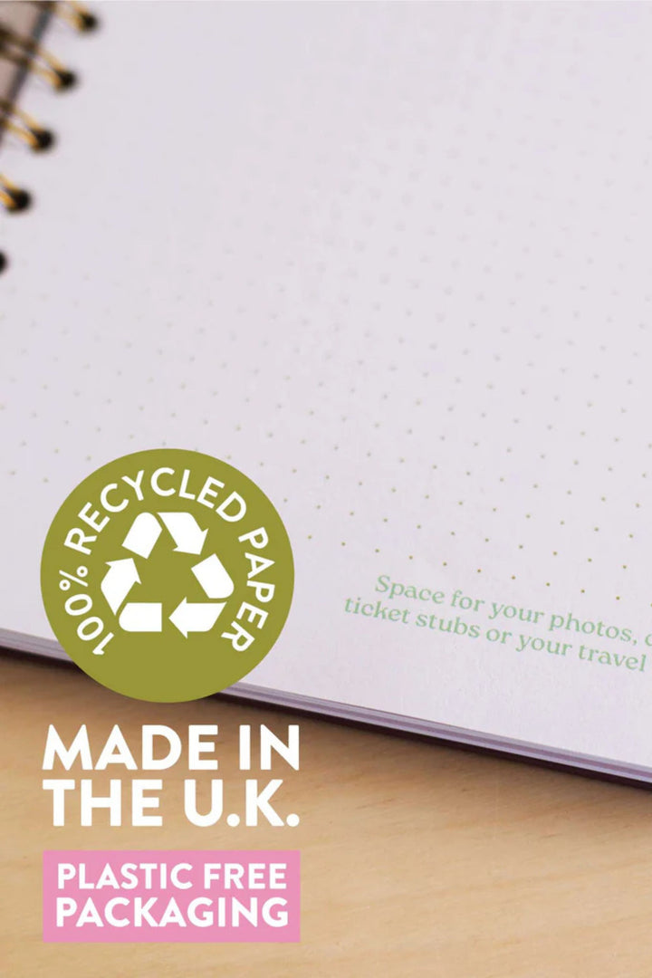 Notebook with recycled paper label and text about plastic-free packaging on a wooden surface.