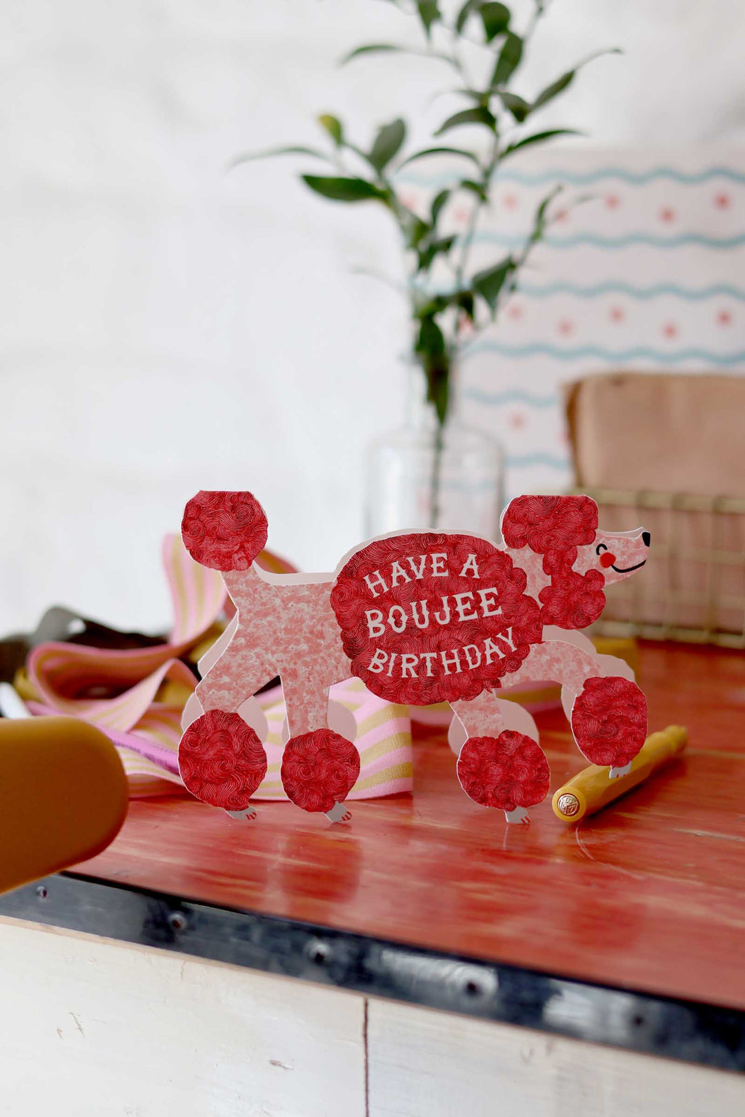 Red and pink birthday card with a dog design on a wooden surface.