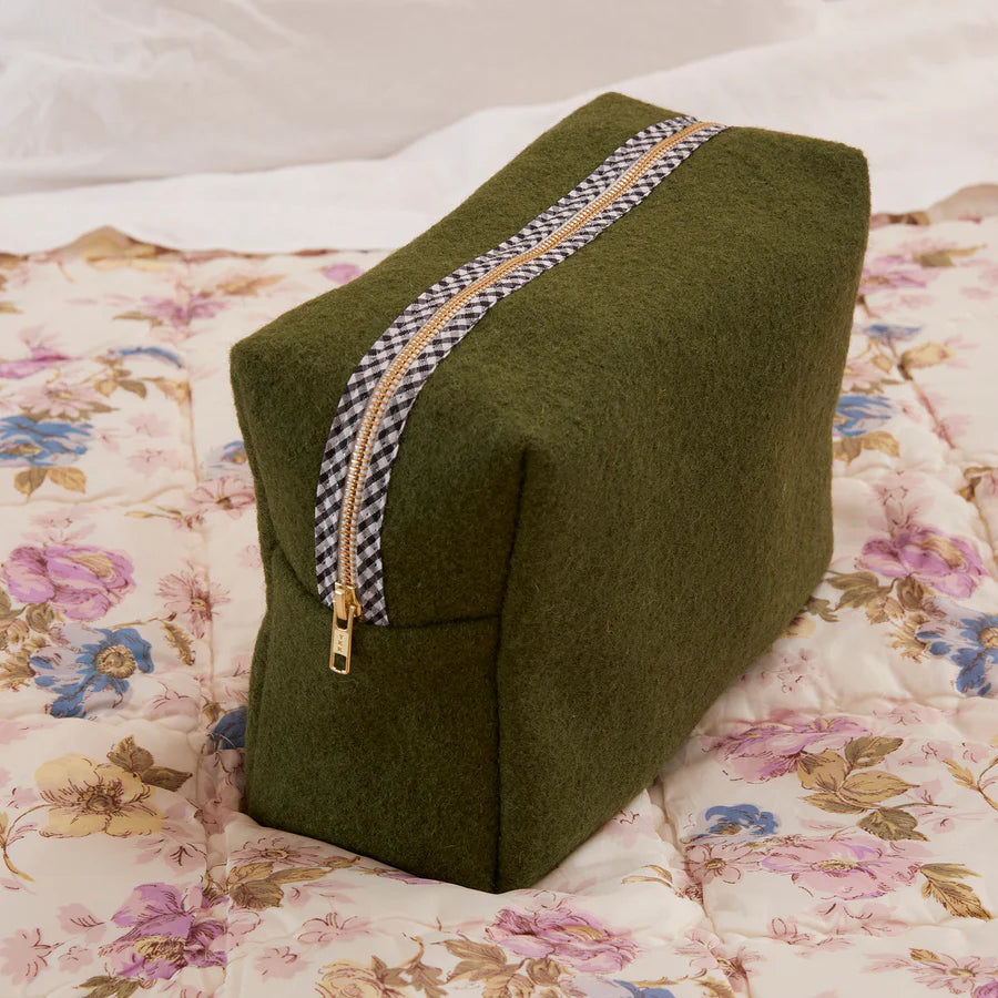 Green wedge-shaped pillow with a zipper on a floral bedspread