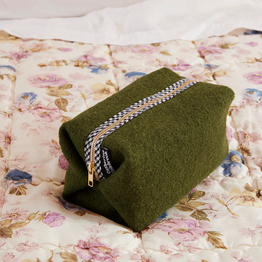 Green pouch with a zipper on a floral blanket