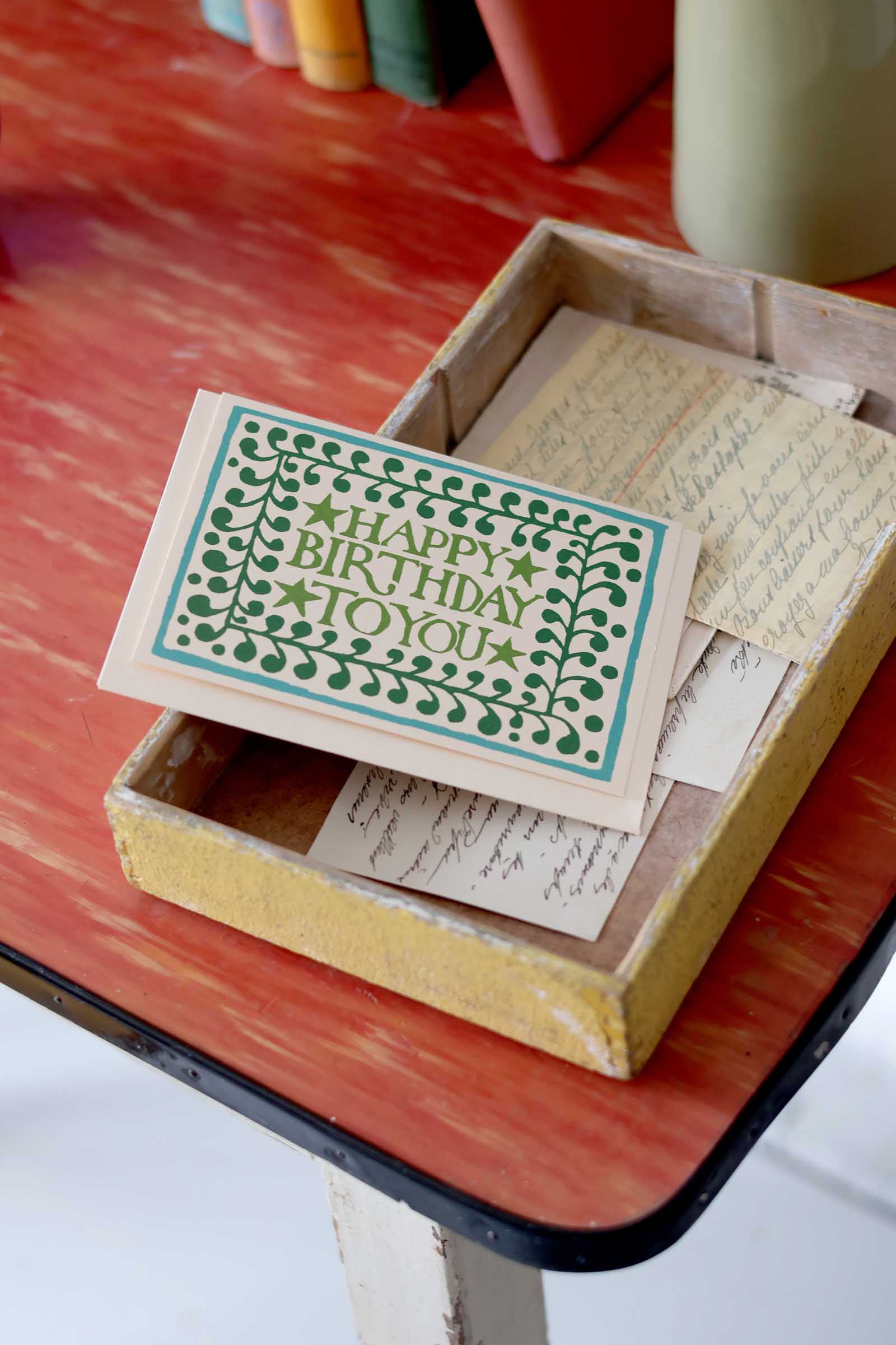 Box with vintage cards, including a 'Happy Birthday' card, on a wooden surface.