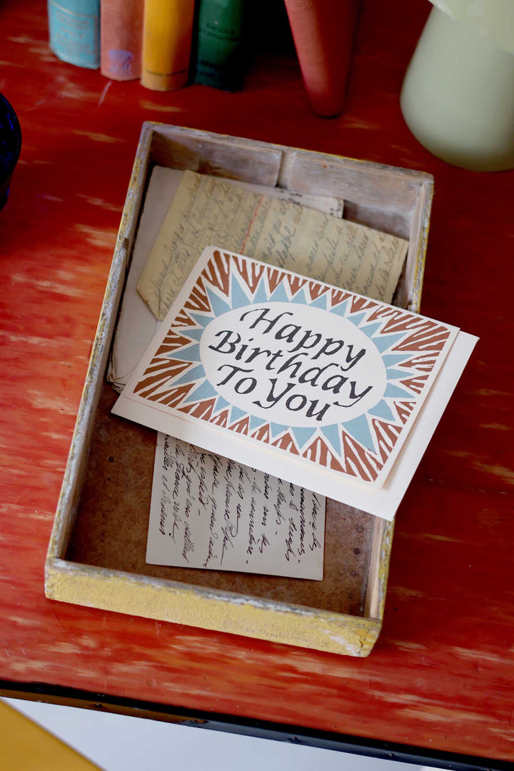 Birthday card with decorative border in a wooden box on a red surface