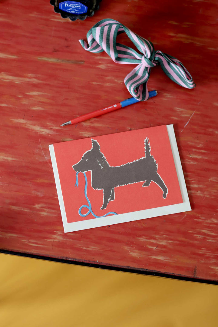 Card with a dog illustration and a toy on a wooden surface