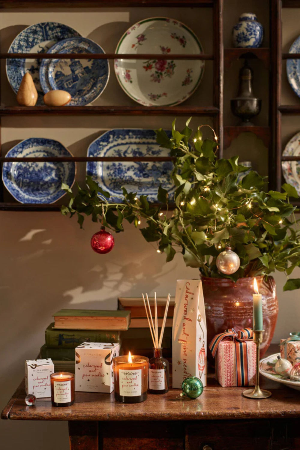 Decorative setting with candles, books, and ornaments on a wooden surface.