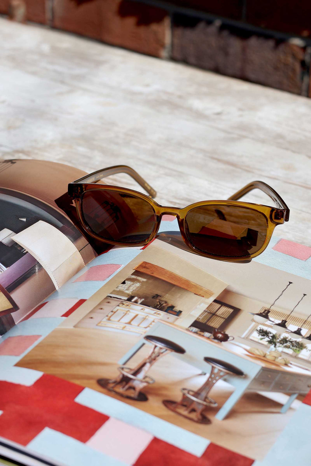 Sunglasses on top of a magazine with interior design images