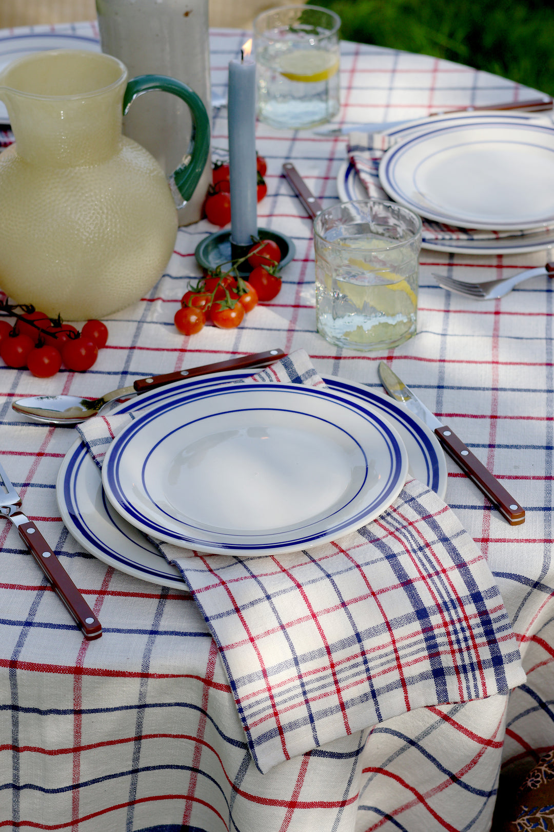 Dining table setting with plates, cutlery, and a plaid tablecloth.