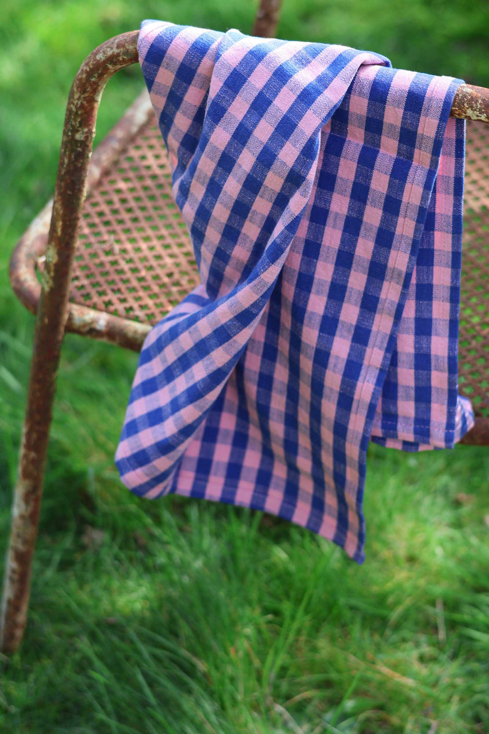 Blue and white checkered towel draped over a metal chair outdoors.