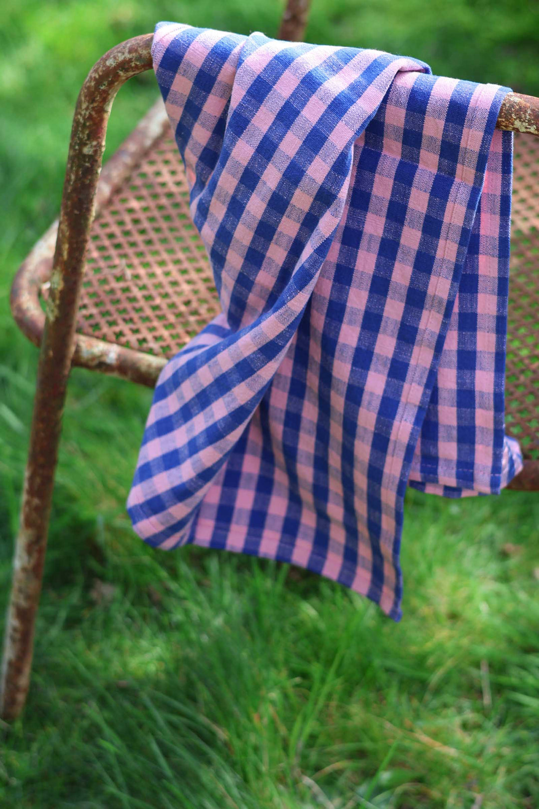 Blue and white checkered towel draped over a metal chair outdoors.