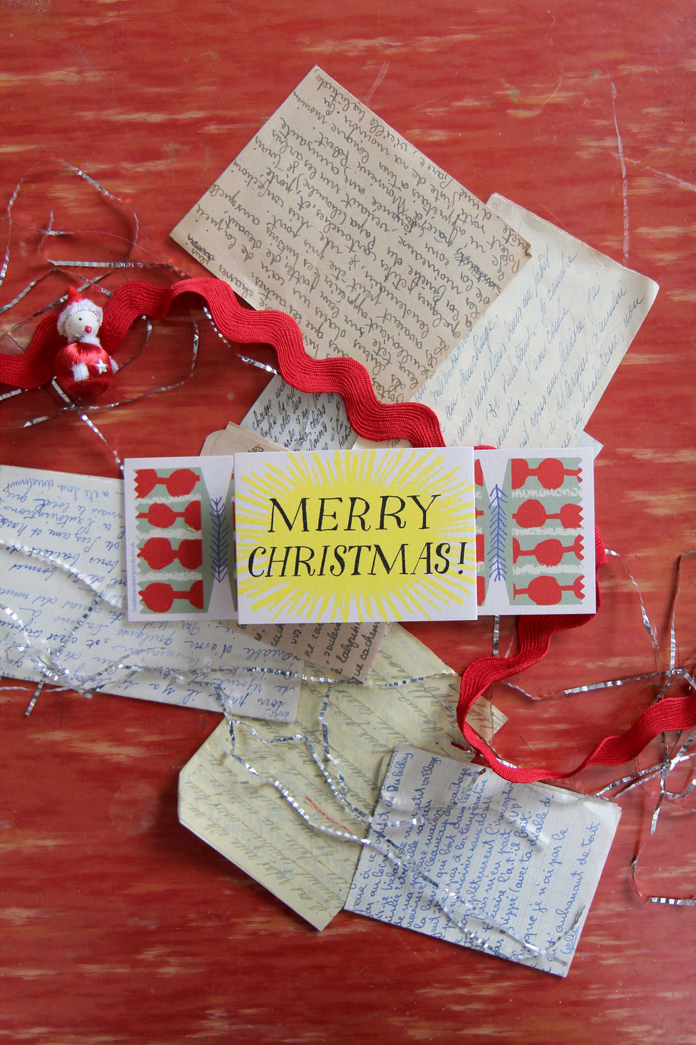 Christmas card with red ribbons and decorative elements on a wooden surface